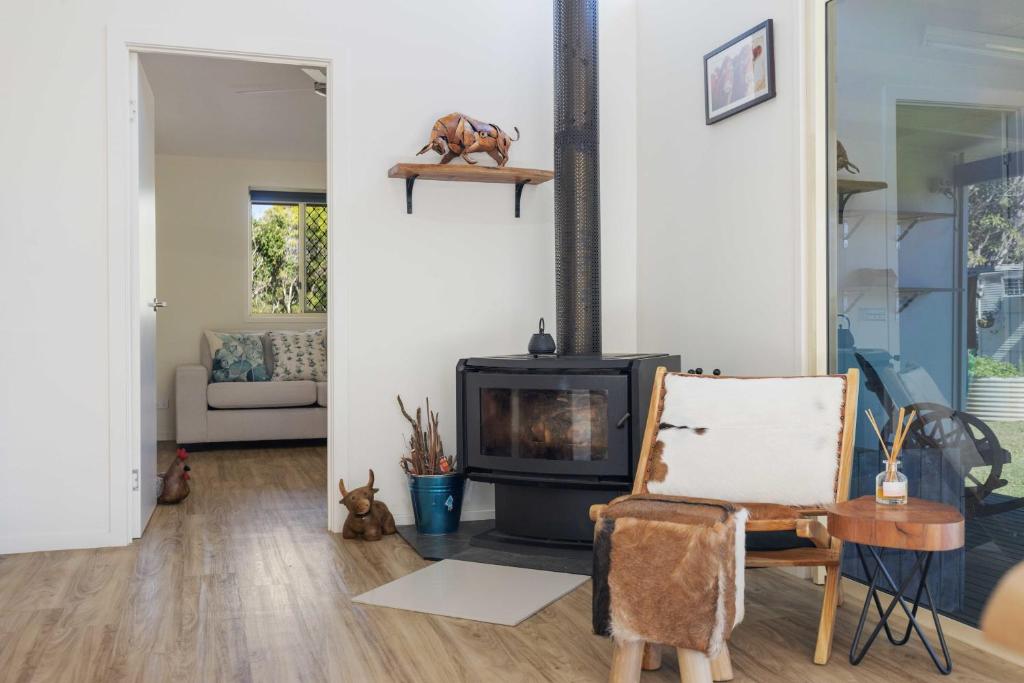 een woonkamer met een open haard en een stoel bij Fiery, cozy starry nights - Farm stay! in Bellthorpe