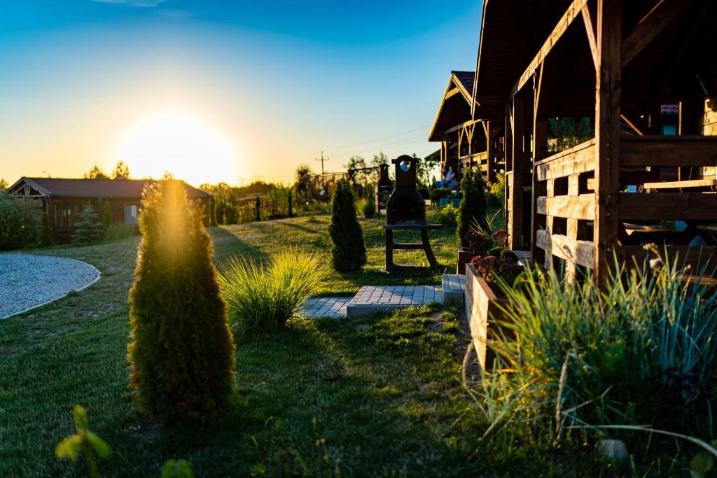 a house with the sun setting in the yard at Domki Nad Stawem Mazury D5 in Mrągowo