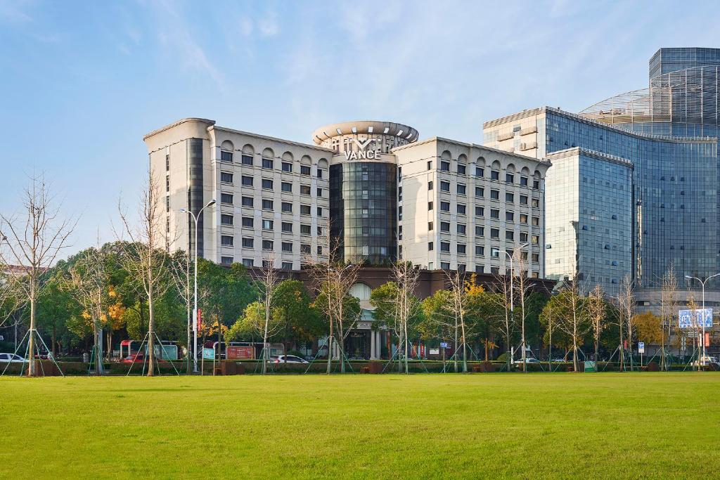 un grande edificio con un campo verde davanti di Vance Hotel - Taizhou a Taizhou