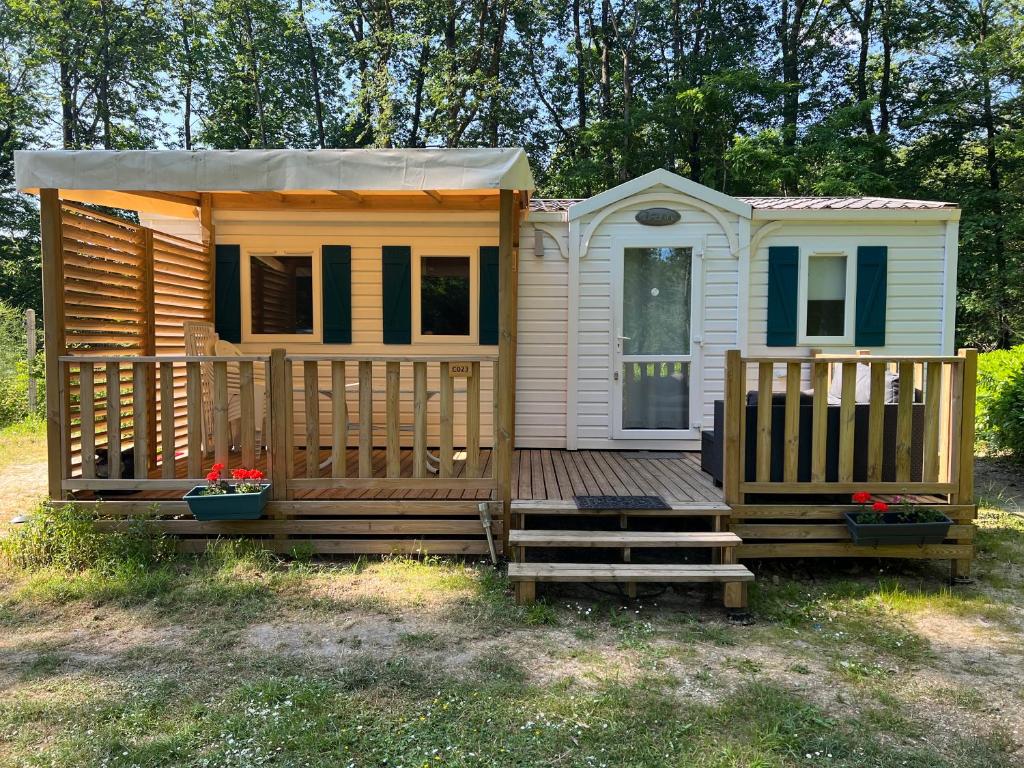 a large wooden cabin with a porch and a deck at Mobil home 2 in Saint-Chéron