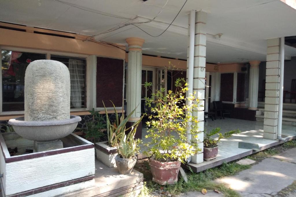 a porch of a house with a fountain and potted plants at DK Hotel Singaraja in Singaraja