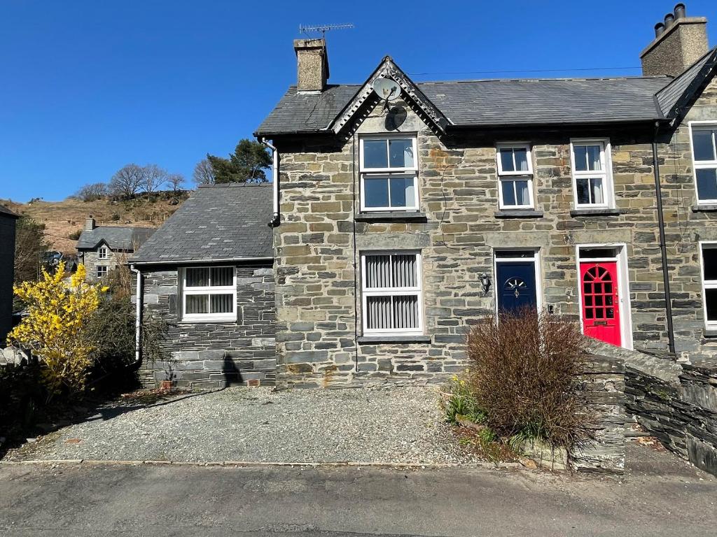 a stone house with a red door on a street at 7 Castle Terrace in Dolwyddelan