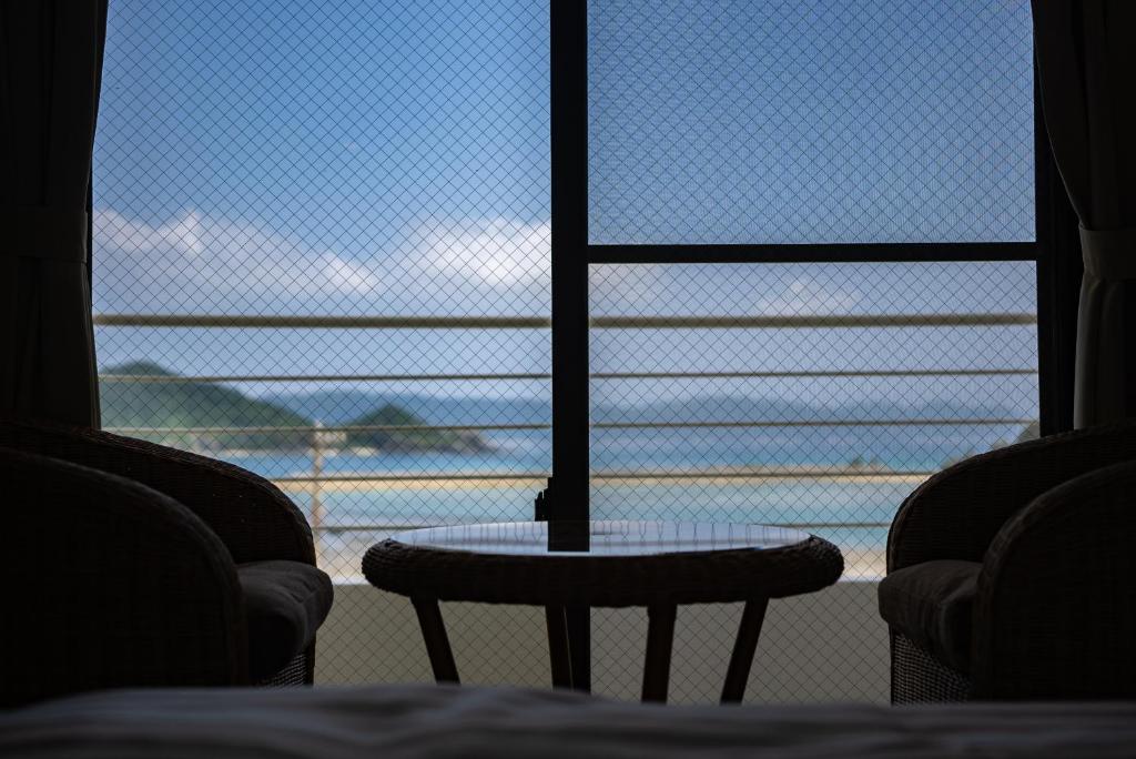 a table and chairs in front of a window at Kerama Blue Resort in Zamami