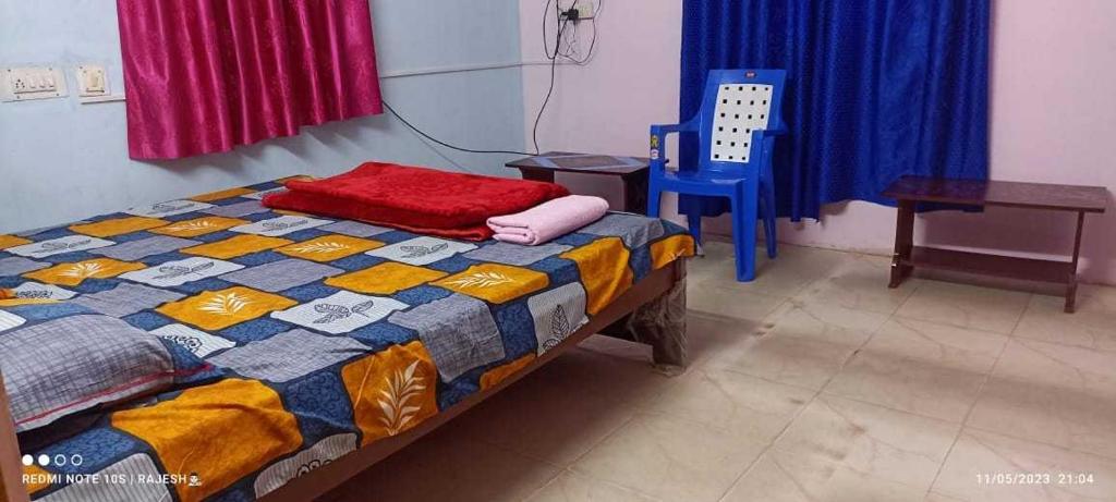 een slaapkamer met een bed en een blauwe stoel bij OYO Aaradhya Hotel &restaurant in Parādīp Garh