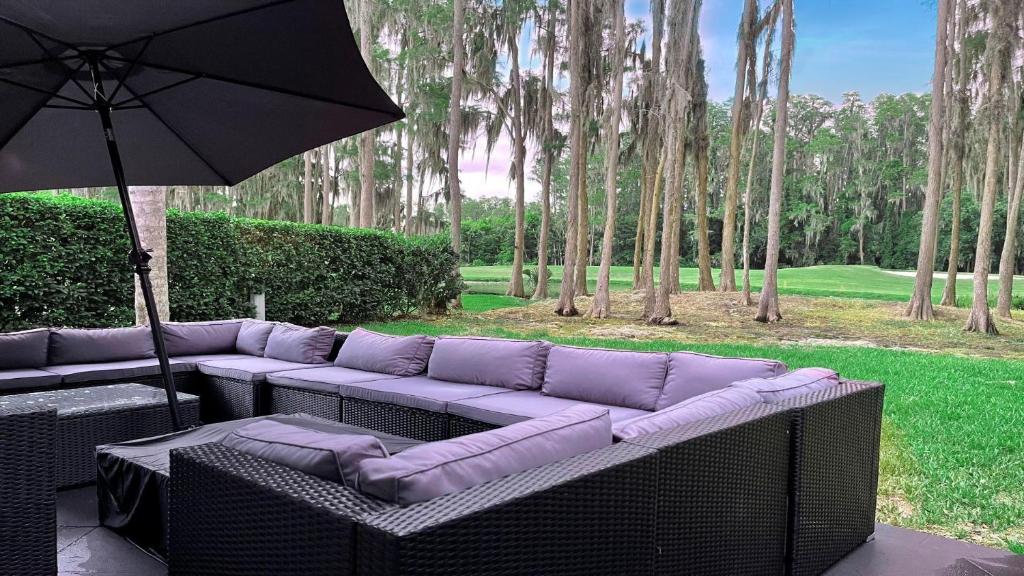 a couch with an umbrella on a patio at 7 Room TampaGolfVillas by AmericanVacationliving in Wesley Chapel