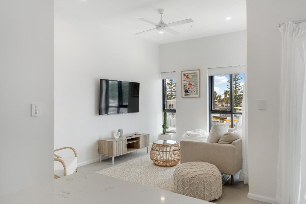 a white living room with a couch and a tv at Sunny Gold Coast Miami Getaway in Gold Coast