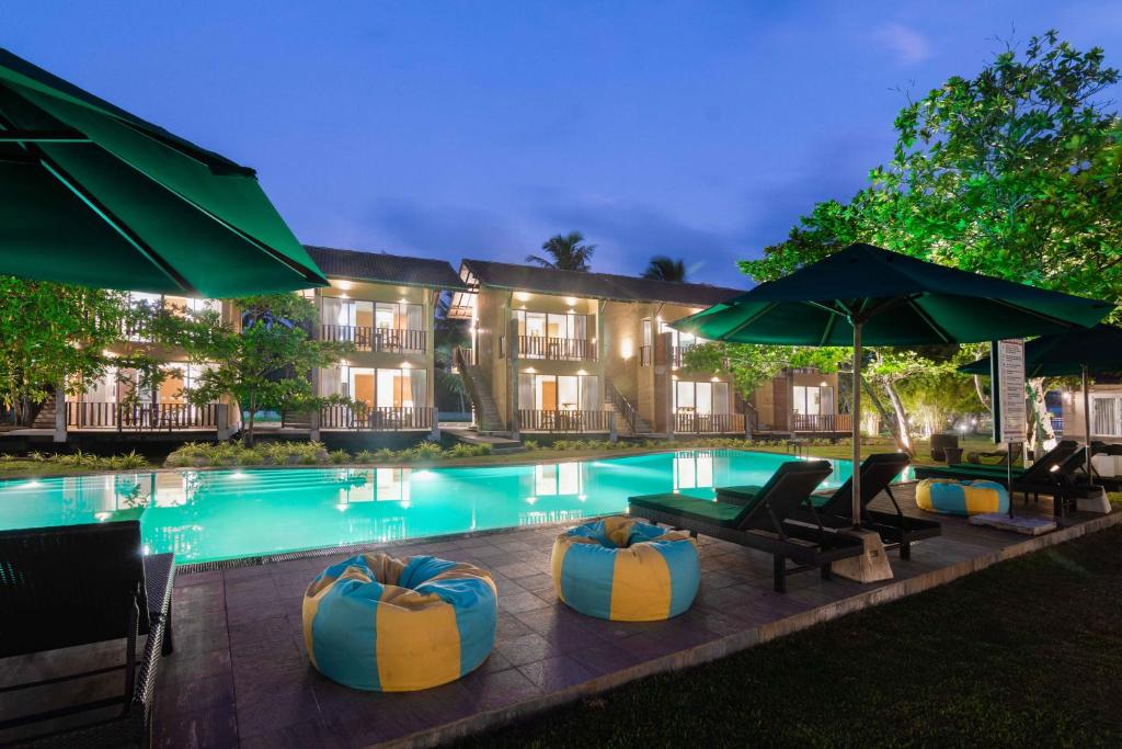 een zwembad van het resort met stoelen en parasols bij South Lake Resort Koggala in Koggala