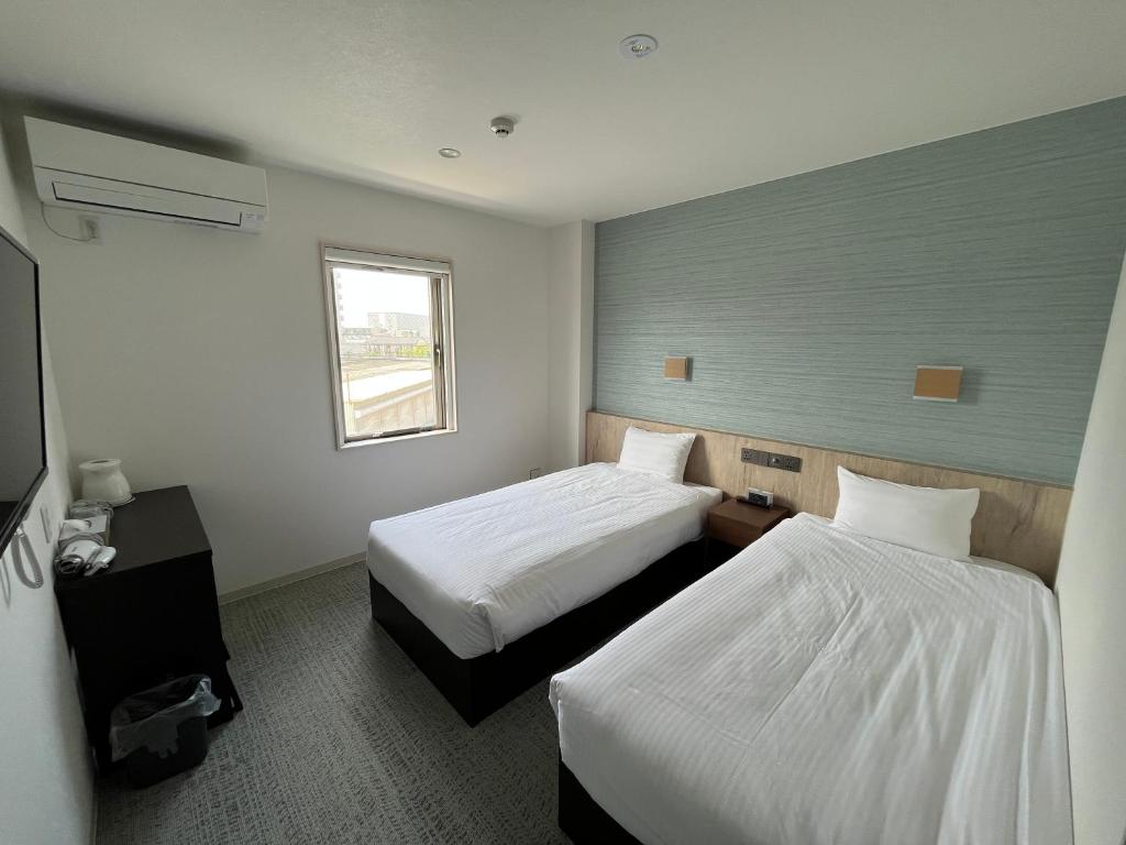 a hotel room with two beds and a window at Plaza In Kanku Hotel in Sano