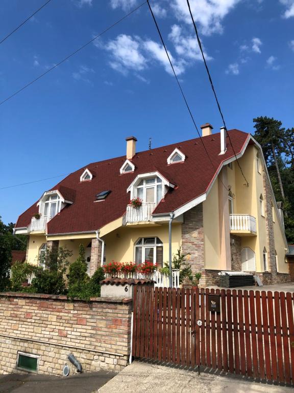 una casa con techo rojo y valla en Eva Rooms, en Budakeszi