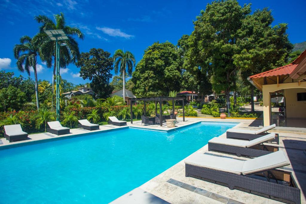 a swimming pool at a resort with lounge chairs and palm trees at Auberge Villa Cana in Cap-Haïtien