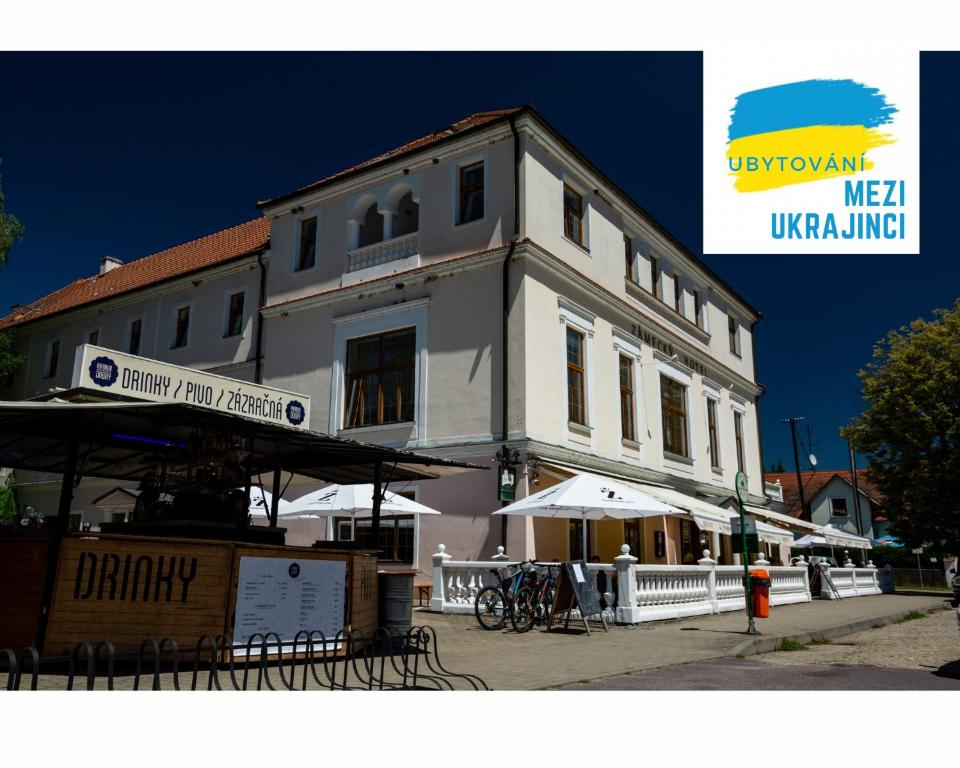 a white building with tables and umbrellas in front of it at Grandhotel Sluchátko - EX Zámecký hotel in Vranov nad Dyjí