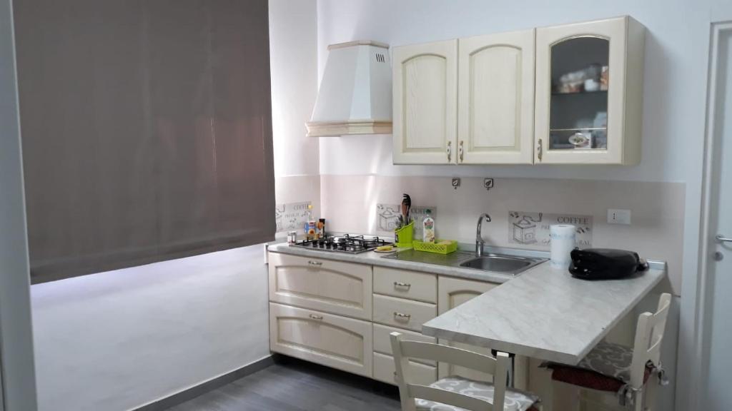 una cocina con armarios blancos y fregadero en Fuori Ortigia Room 2, en Siracusa