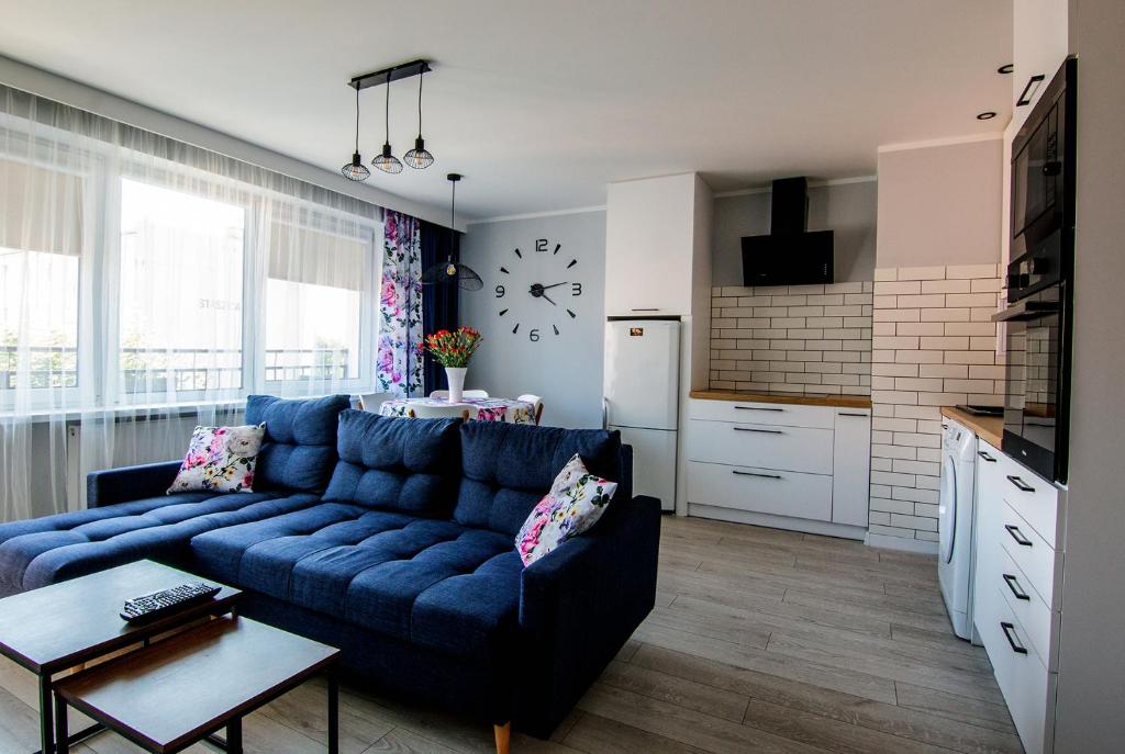 Il comprend un salon avec un canapé bleu et une cuisine. dans l'établissement Apartament Cztery Pory Roku w Giżycku, à Giżycko