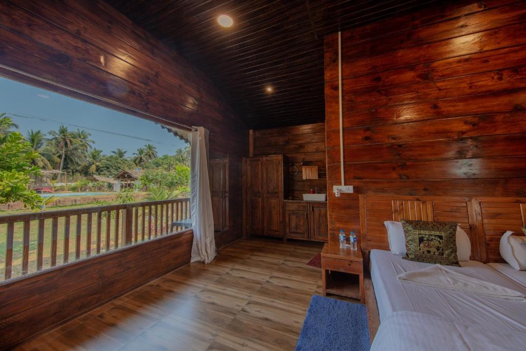 a living room with a bed and a balcony at Radhika Eco Resort(Odonata) in Arambol