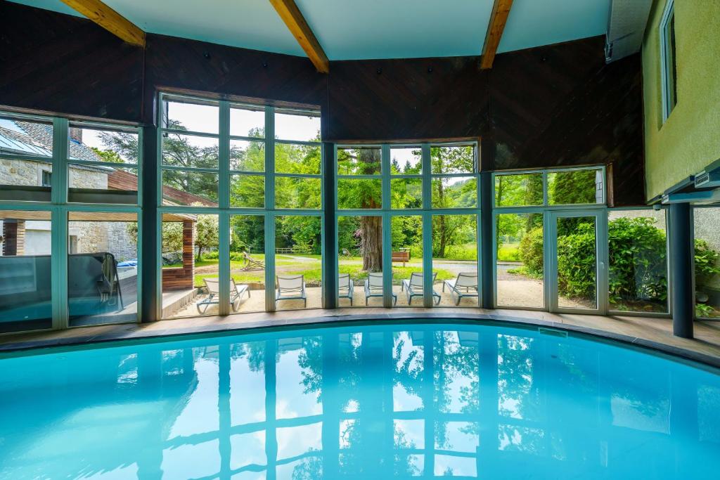 una piscina en una casa con ventanas en Hotel Les Jardins De La Molignée en Dinant