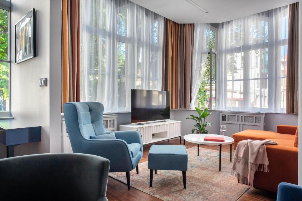 a living room with blue chairs and a tv at By Monte Apartment in Sopot