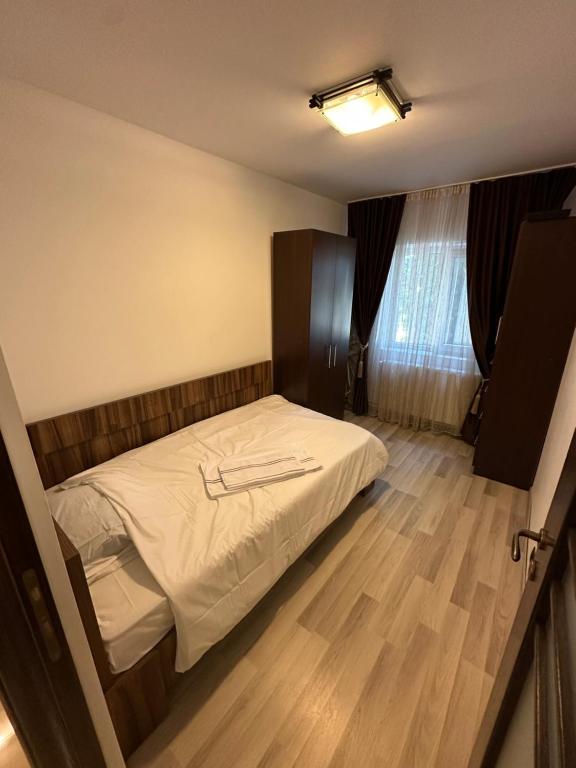 1 dormitorio con 1 cama y suelo de madera en Page2 Apartament, en Târgovişte