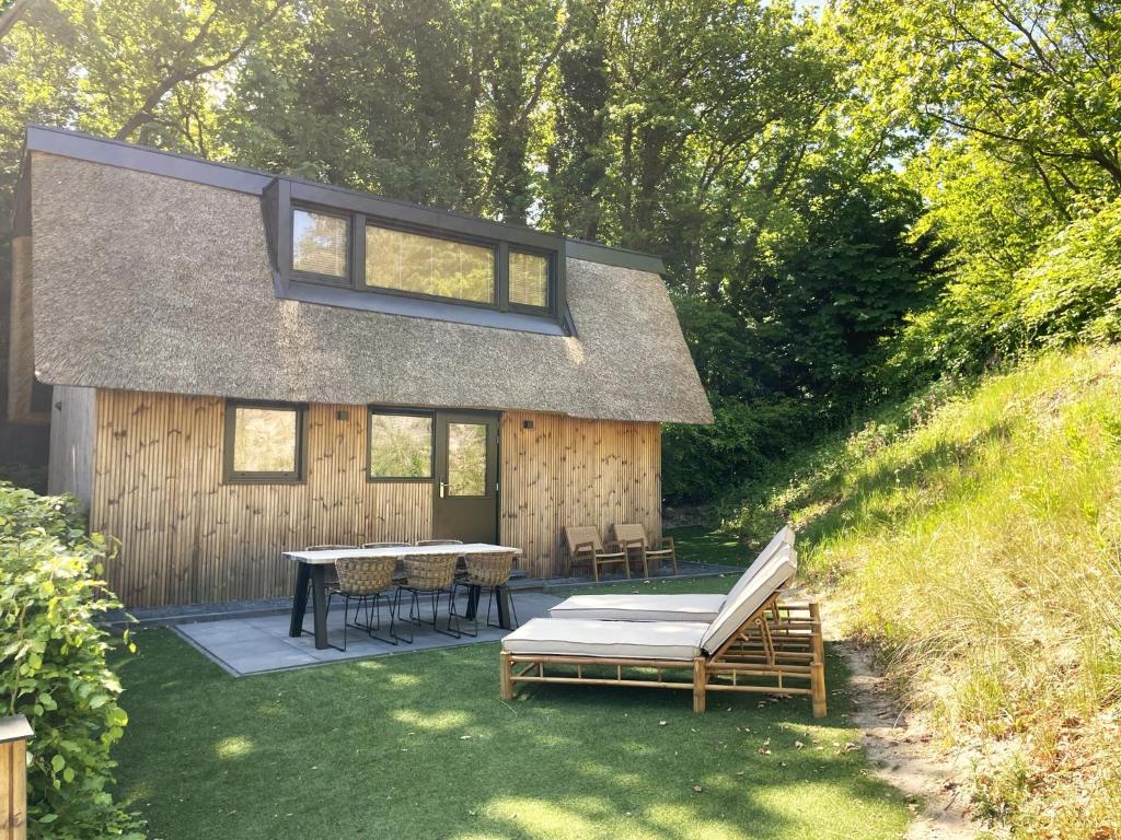 une maison avec une terrasse, une table et des chaises dans l'établissement Park Heerehof, à Schoorl