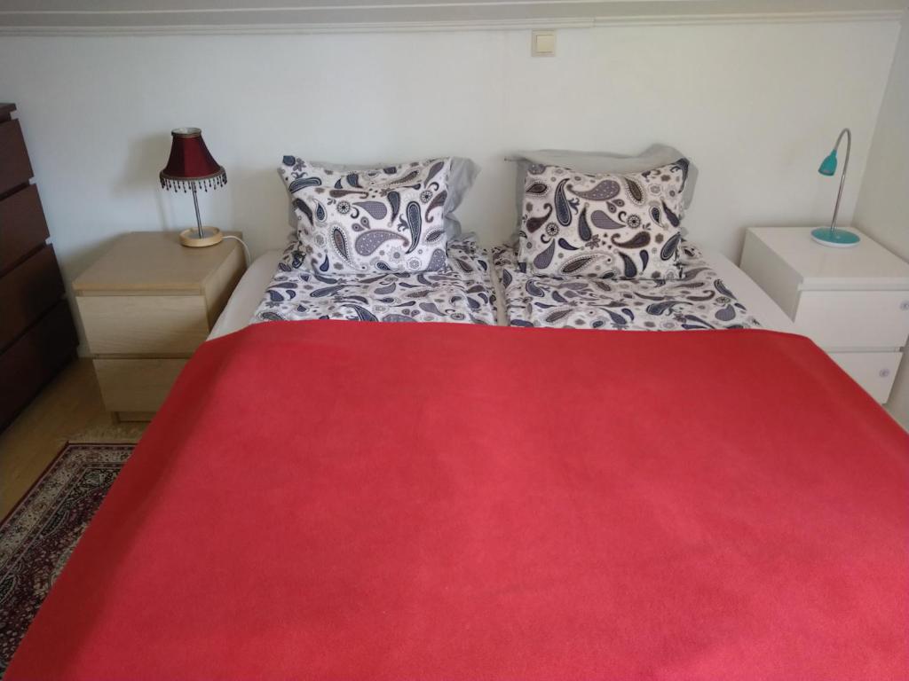 a red bed with two pillows and a red blanket at Helsinki Blue House in Helsinki