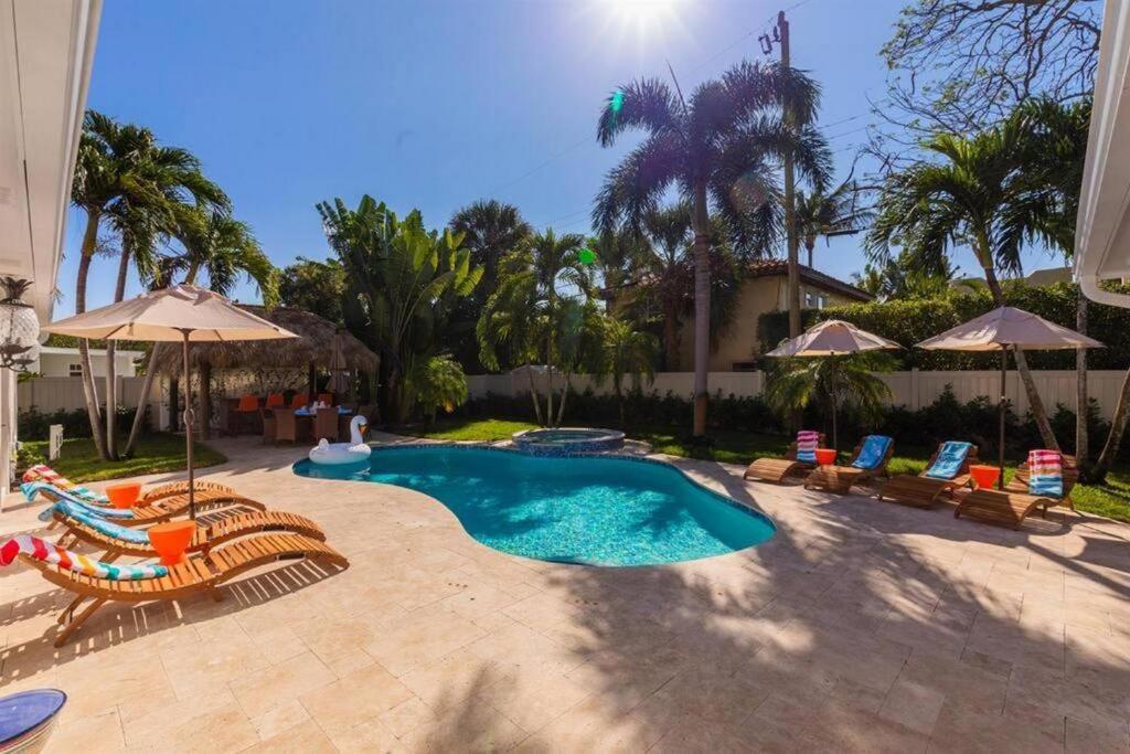 a swimming pool with chairs and umbrellas at Pineapple Palms Resort Style Pool Villa! Sleeps 12 in West Palm Beach