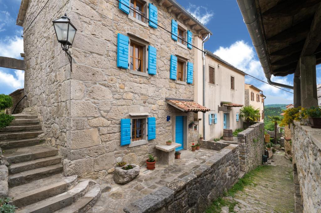 una vieja casa de piedra con persianas azules en una calle en House Vera, en Hum