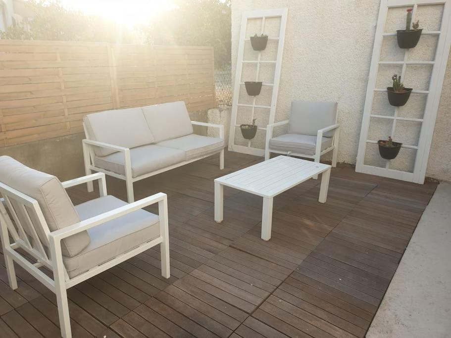 2 sillas blancas y un banco en un patio en Appartement, prive terrasse, parking et jardin, en Le Boulou