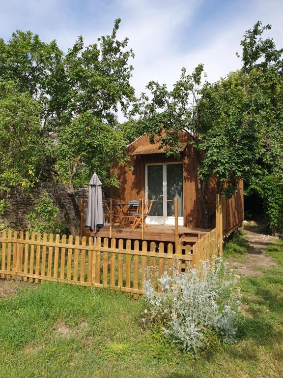 een houten huis met een hek en een paraplu bij Studio en bois independant avec terrasse et jardin in Villevieille
