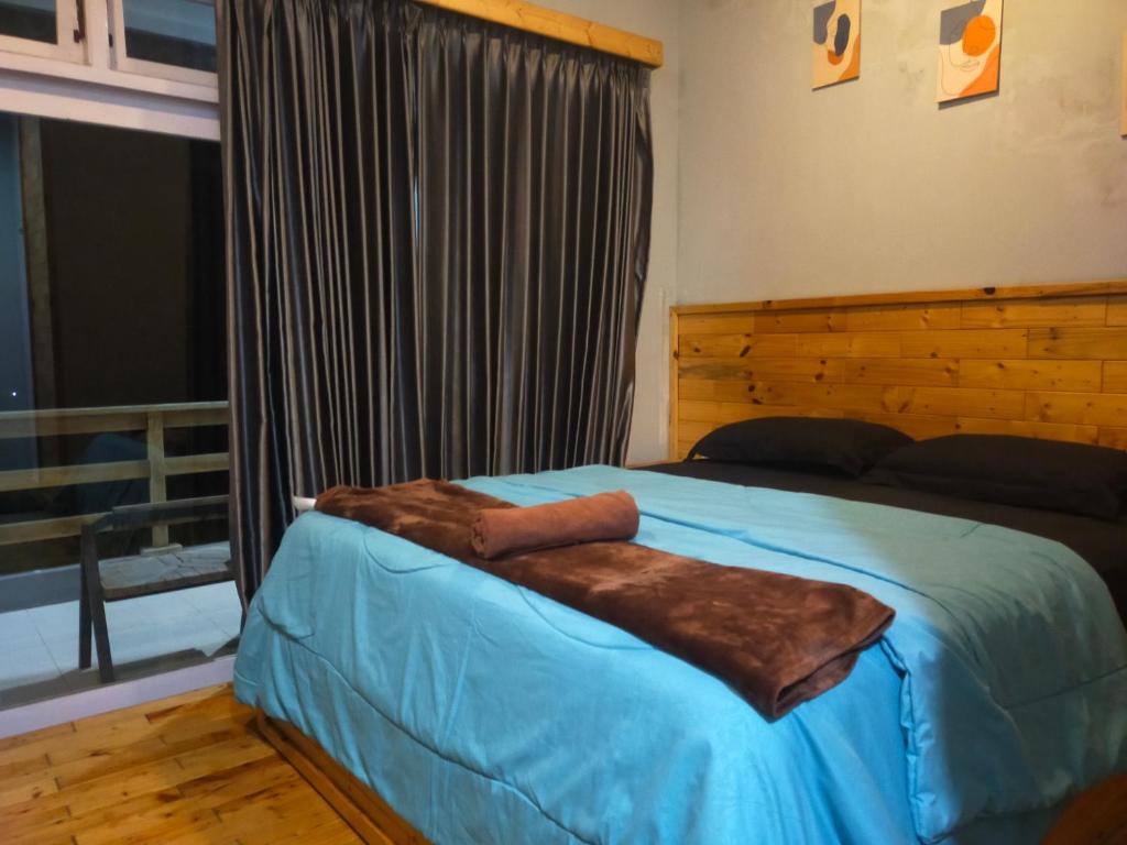 1 dormitorio con cama azul y manta marrón en Bromo Semesta Guesthouse en Probolinggo