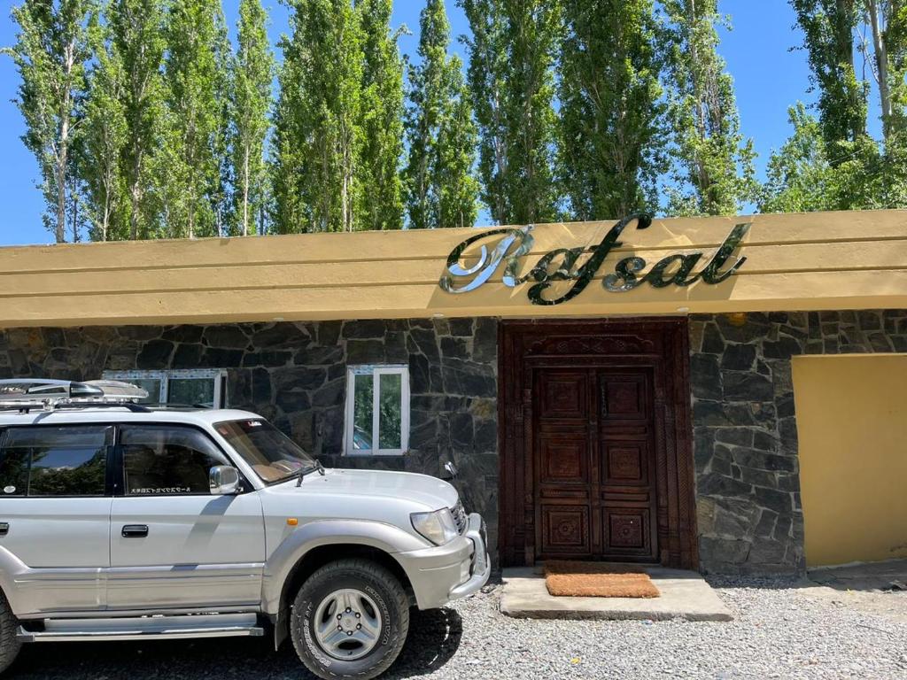 a white suv parked in front of a building at Rafsal A Countryside Cottage in Skardu