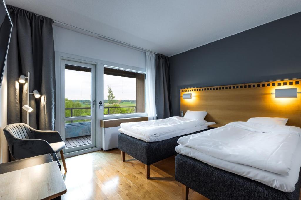 una camera d'albergo con due letti e una finestra di Hotelli Siuntio a Sjundeå