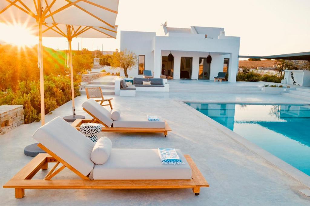a villa with a swimming pool and white furniture at Amalthea, Outstanding Seaside Luxury Villa, Paros in Santa Marina