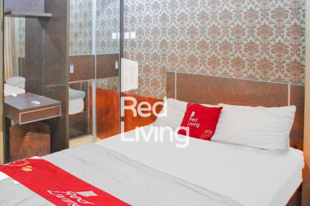 a bedroom with a white bed with red pillows at RedLiving Apartemen Tamansari Panoramic - Anwar Rental in Bandung