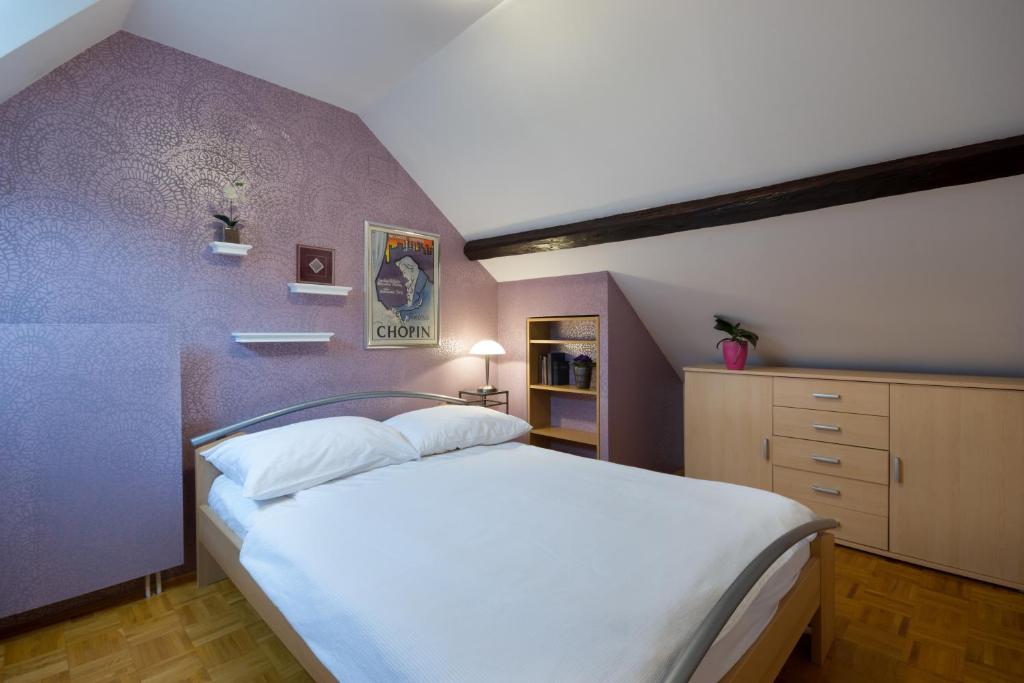 Apartment Nina with private terrace Tour As Ljubljana في ليوبليانا: غرفة نوم بسرير ابيض وجدار ارجواني