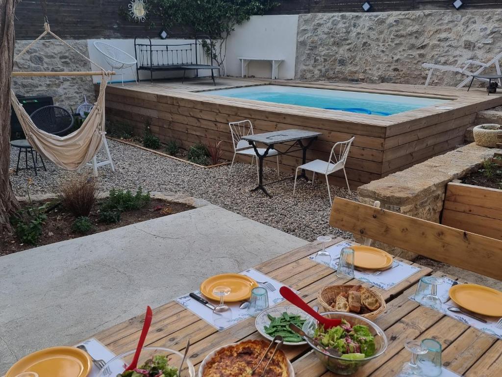 una mesa con platos de comida junto a una piscina en Chez Lola-Maison d'hôtes Corbières, en Durban-Corbières