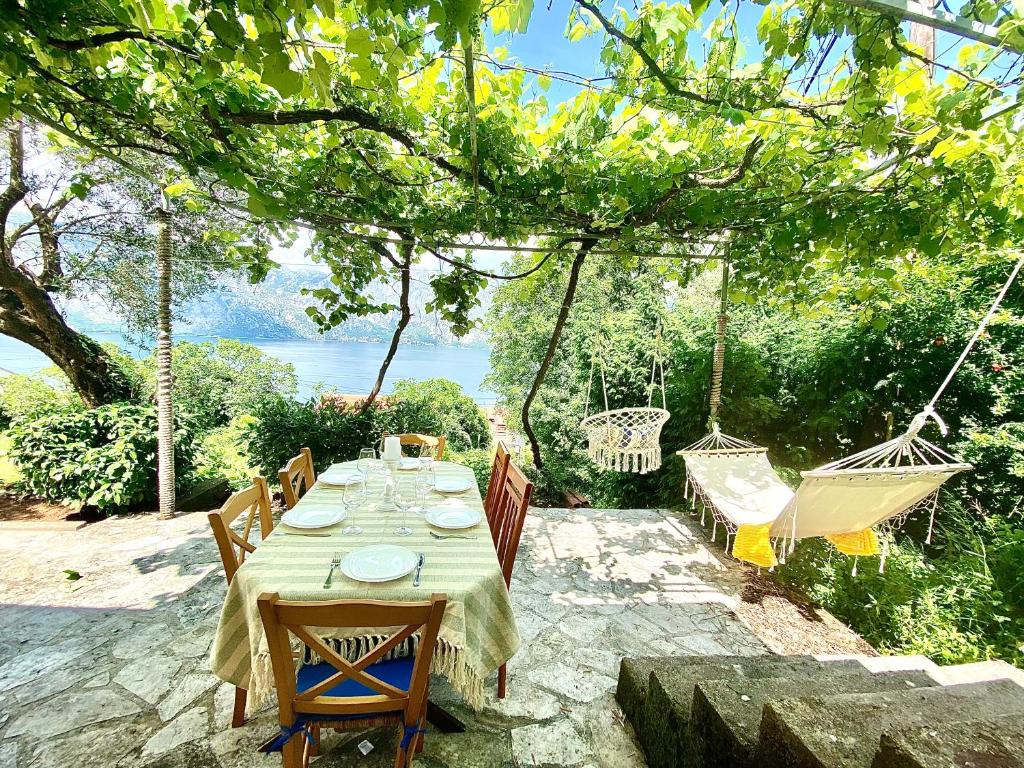 a dining table with chairs and hammocks in a backyard at Sea view country house in Prčanj