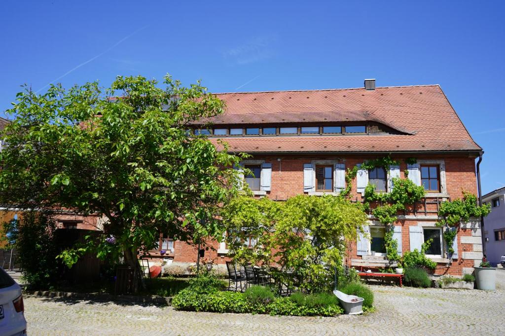 un bâtiment en briques avec un arbre devant lui dans l'établissement Ferienwohnungen Schuh, à Ipsheim