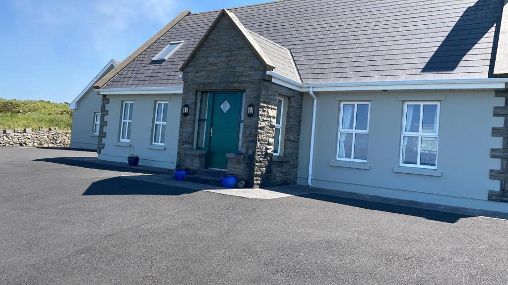 a house with a blue door on a driveway at The Cliffs of Moher House, Doolin in Doolin