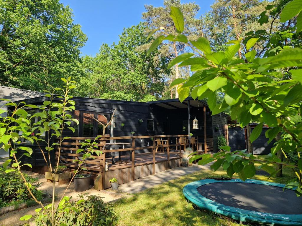 a black house with a swimming pool in a yard at Heerlijk Huisje in het bos op Chaletpark Kempenbos in Diessen