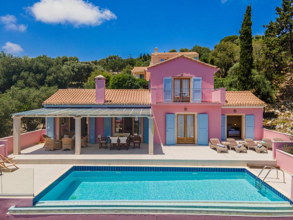 a pink house with a swimming pool in front of it at Villa Helios Sea View & Private Pool near Fiskardo in Fiskardo