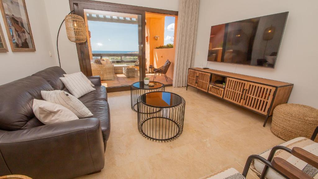 a living room with a leather couch and a television at Coto Real Thasos 222 in Manilva