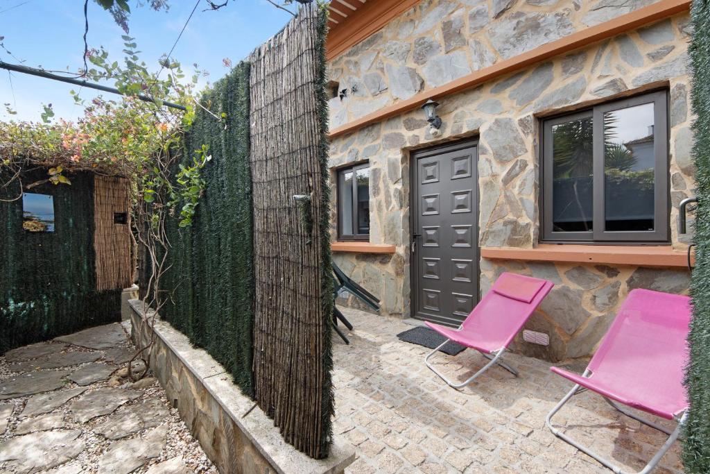 une maison avec deux chaises roses et une clôture dans l'établissement Casa Luz Apartamento 2, 