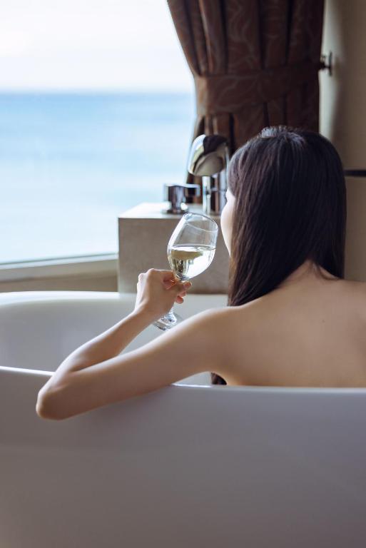 a woman sitting in a bath tub holding a glass of wine at H Resort in Checheng