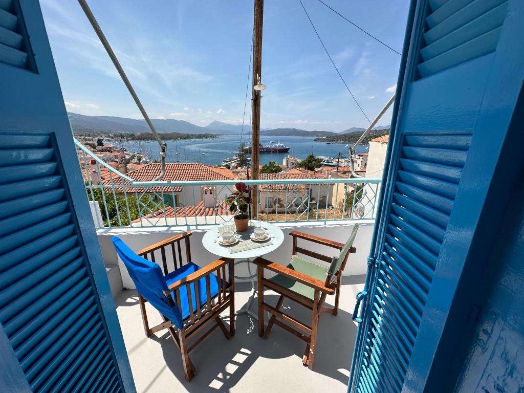 balcón con mesa, sillas y vistas al agua en Brinia Cosy Apartment, en Poros