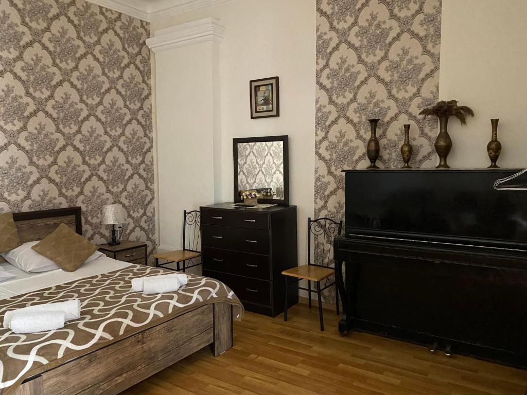 a bedroom with a bed and a dresser and a piano at Guest house Lusia in Tbilisi City