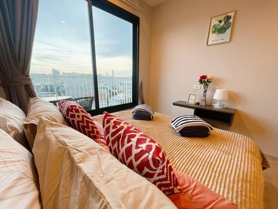 1 cama con almohadas en una habitación con ventana en BASE Central PATTAYA Long Balcony with Infinity Pool & Free Netflix! en Pattaya centro
