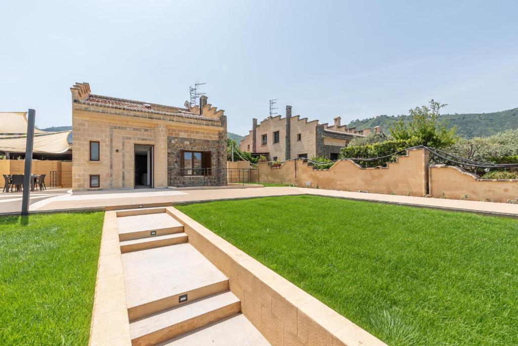 einen Innenhof mit grünem Gras und ein Gebäude in der Unterkunft Villa alla Baia dei Sette Emiri by Wonderful Italy in Cefalú