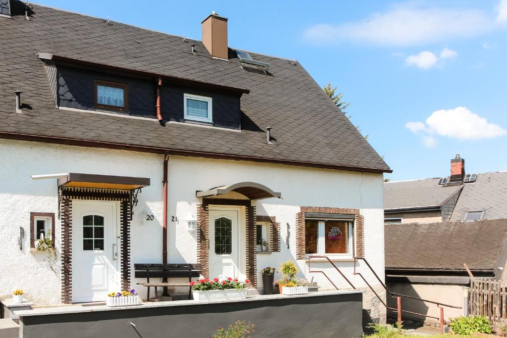 een wit huis met een zwart dak bij Ferienwohnung am Sachsenring 