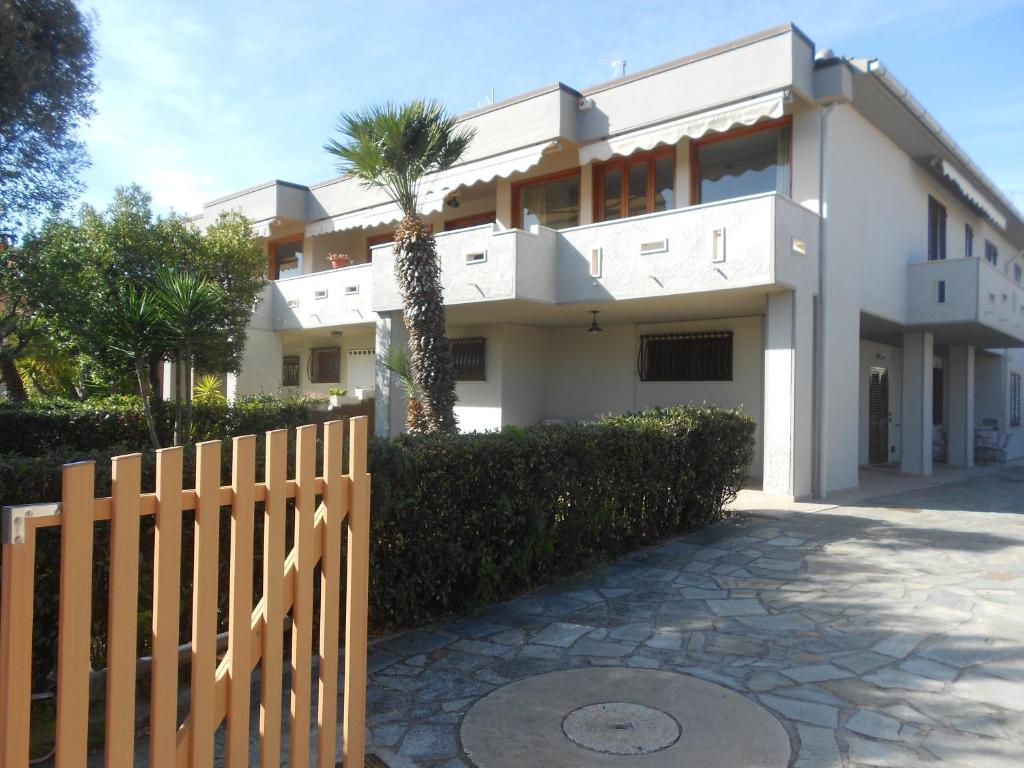 a white house with a fence and a palm tree at Villa happy days in San Vincenzo