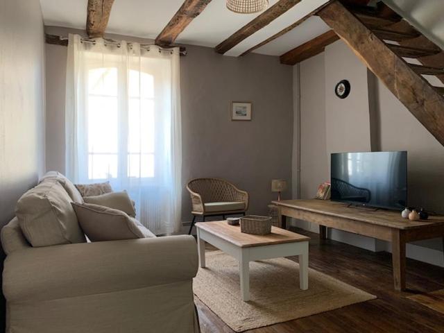 een woonkamer met een bank, een tv en een tafel bij L'Authentique maison de charme in Aubusson