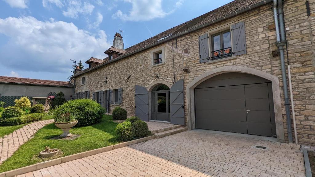 uma casa de tijolos com uma grande garagem num quintal em Le Clos des écureuils - chambres d'hôtes em Sainte-Marie-la-Blanche